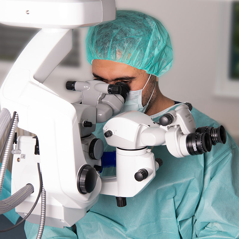 Augenarzt bei einer Operation mit Mikroskop im OP-Saal.